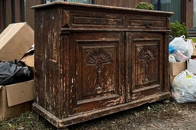 Старый комод, выброшенный на мусор