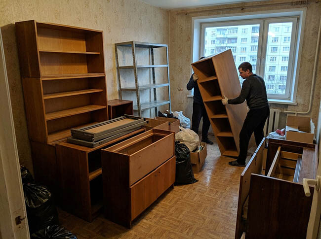 Грузчики выносят старые стеллажи и полки